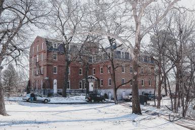 Image of Gaylord Hall, a stately building made of pink brick, set in a snowy landscape.